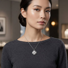 A woman wearing a delicate silver-tone floral pendant necklace with clear stones, styled with a dark gray knit top in a softly blurred boutique setting.
