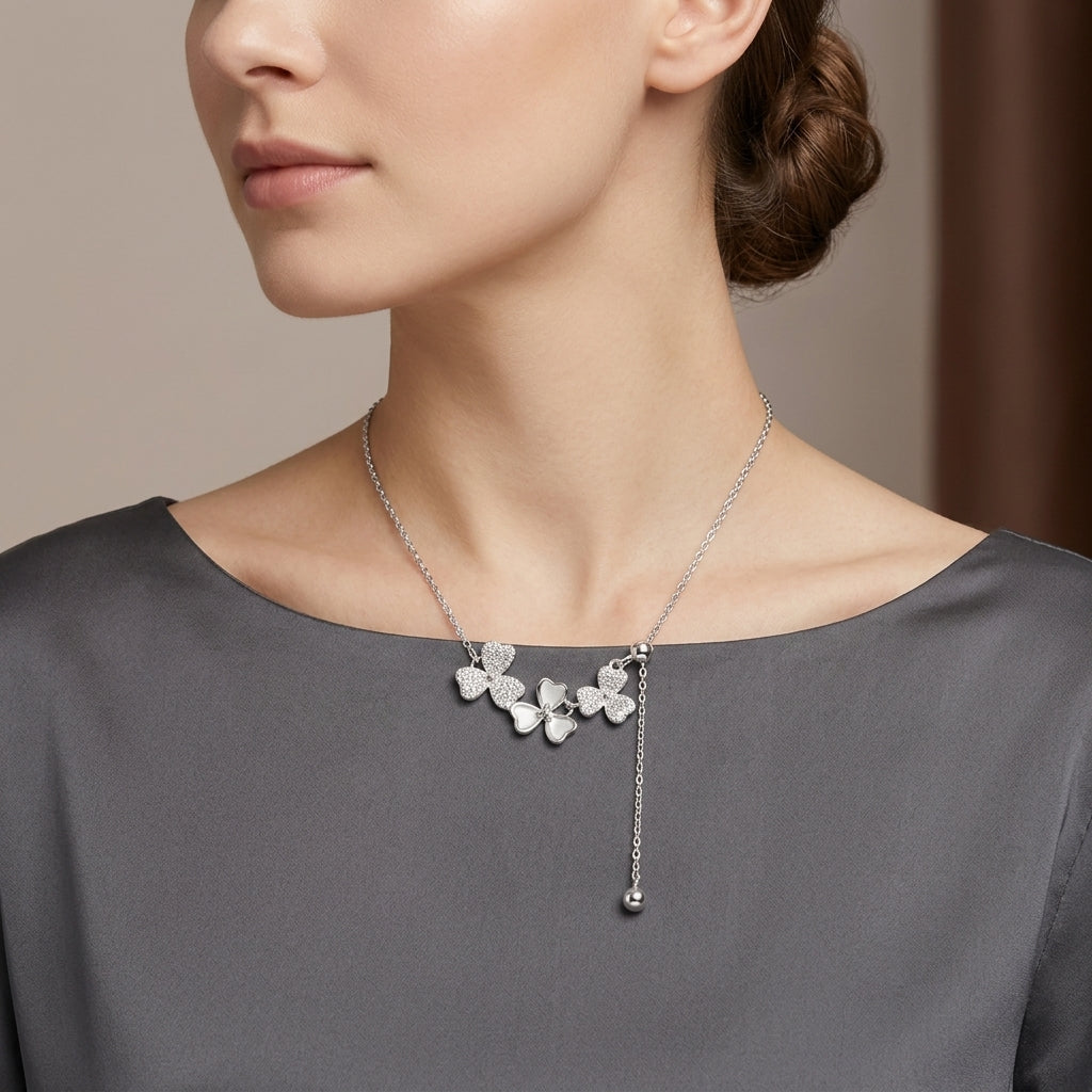 A close-up of a woman wearing a delicate silver necklace with three small butterfly-shaped charms and a dangling bead, paired with a gray top.